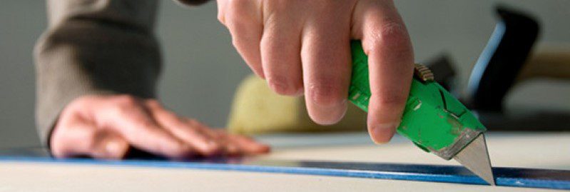 a photo of a hand holding a green box cutter